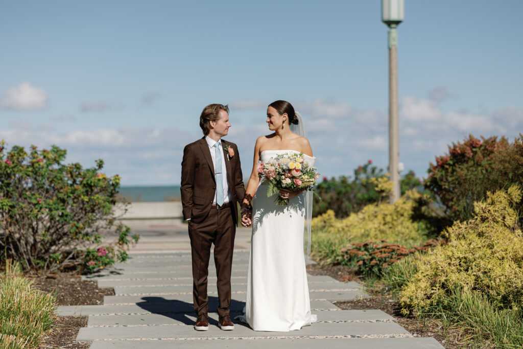 Bride and groom walking together outdoors after their Chicago wedding, surrounded by lakeside greenery and natural light.