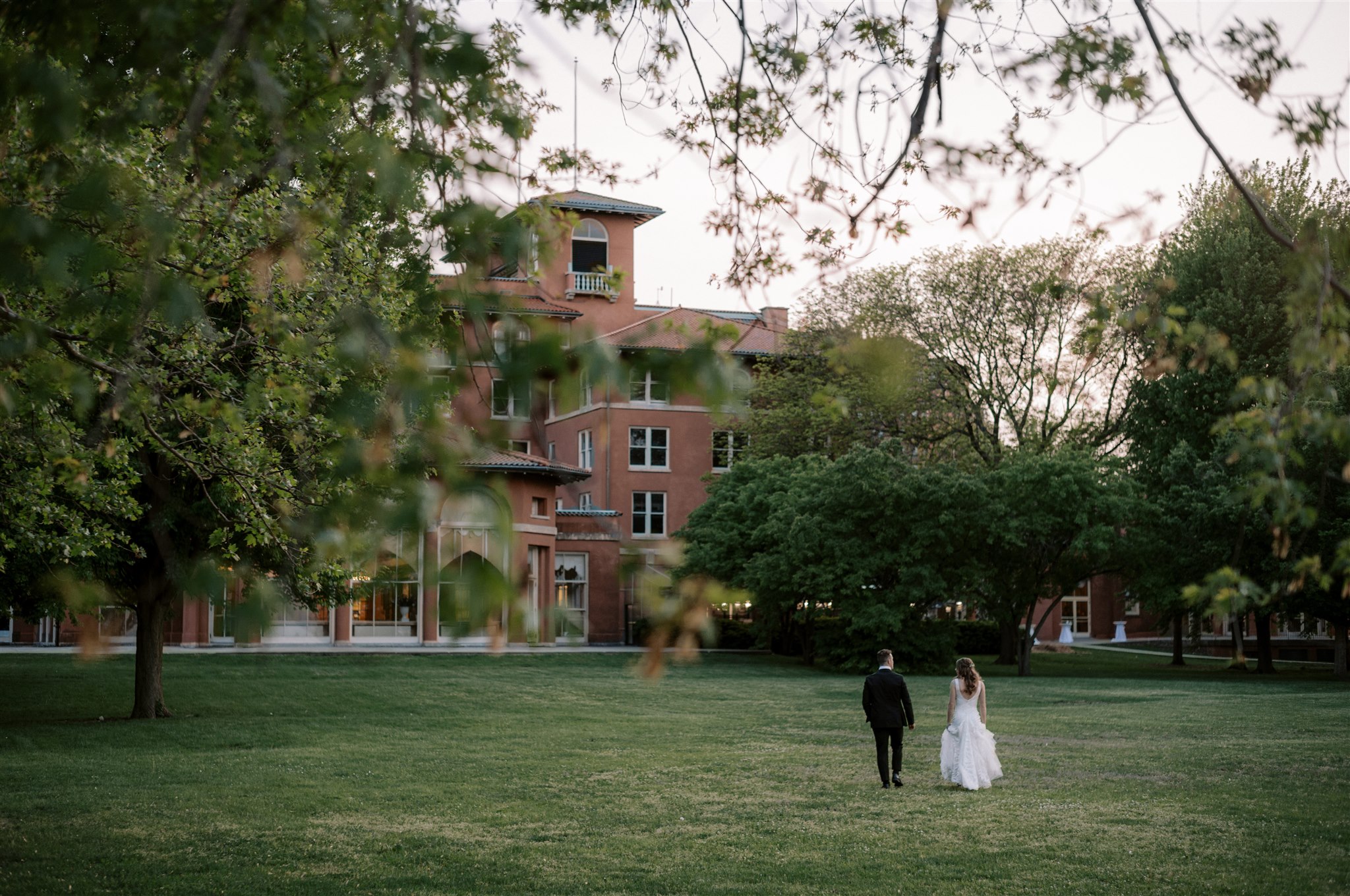 Bride and groom walking across lawn at South Shore Cultural Center wedding venue in Chicago