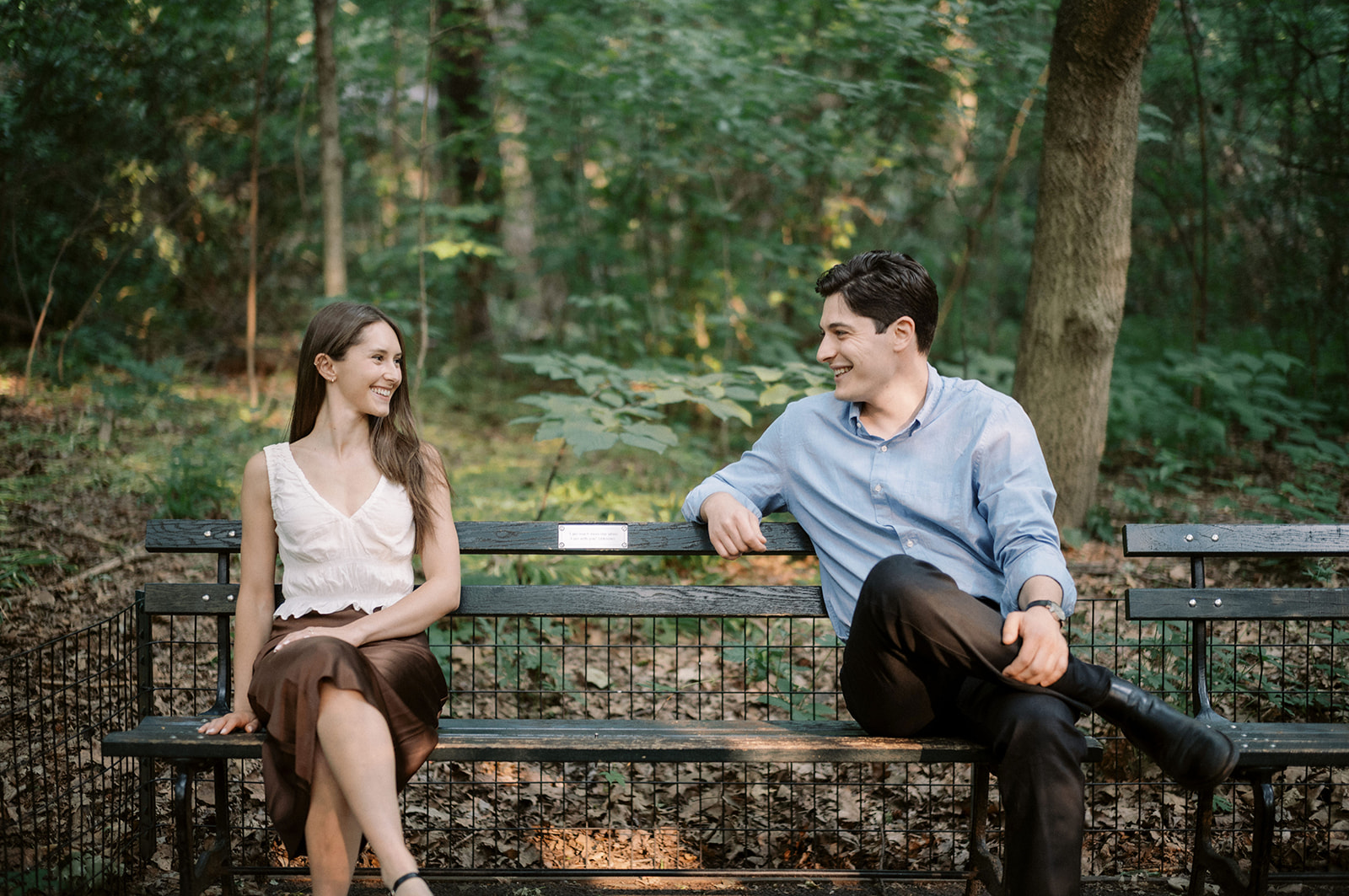 Couple laughing together on a bench during a Central Park engagement session in NYC