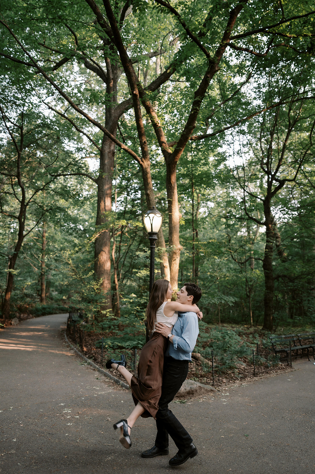 Documentary-style engagement portrait of a couple kissing on a quiet Central Park walkway in New York City