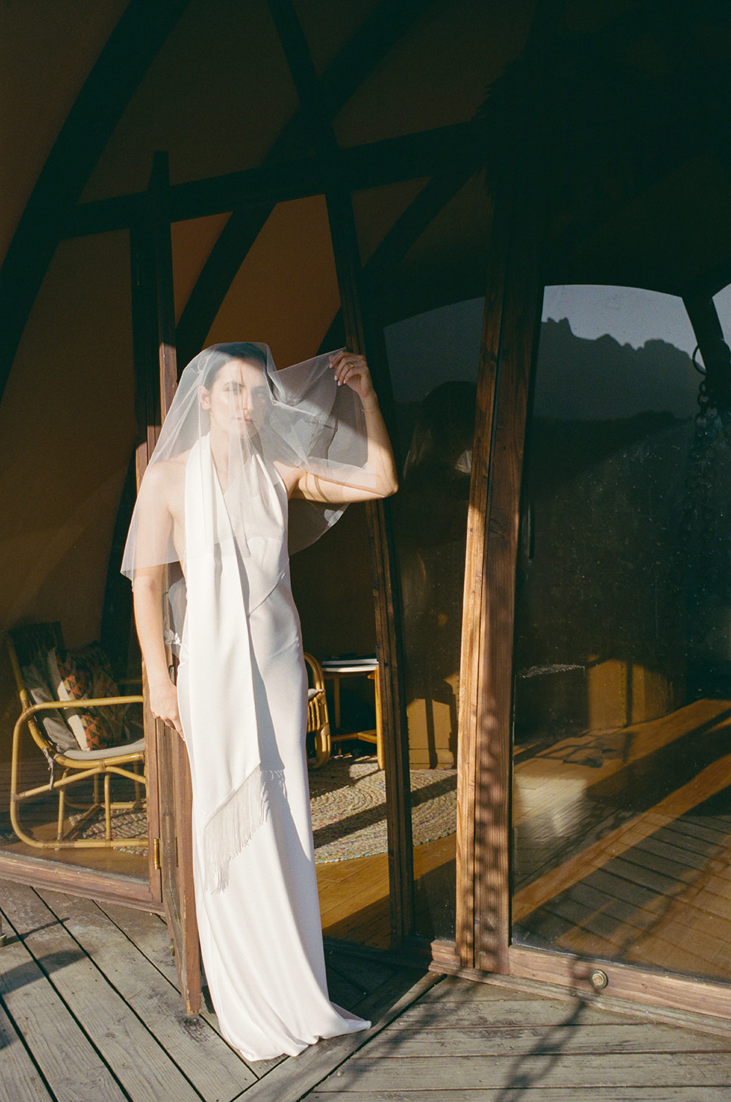 Bride in a simple white dress and veil standing in the doorway at Wild Malibu Film Retreat in Malibu, California