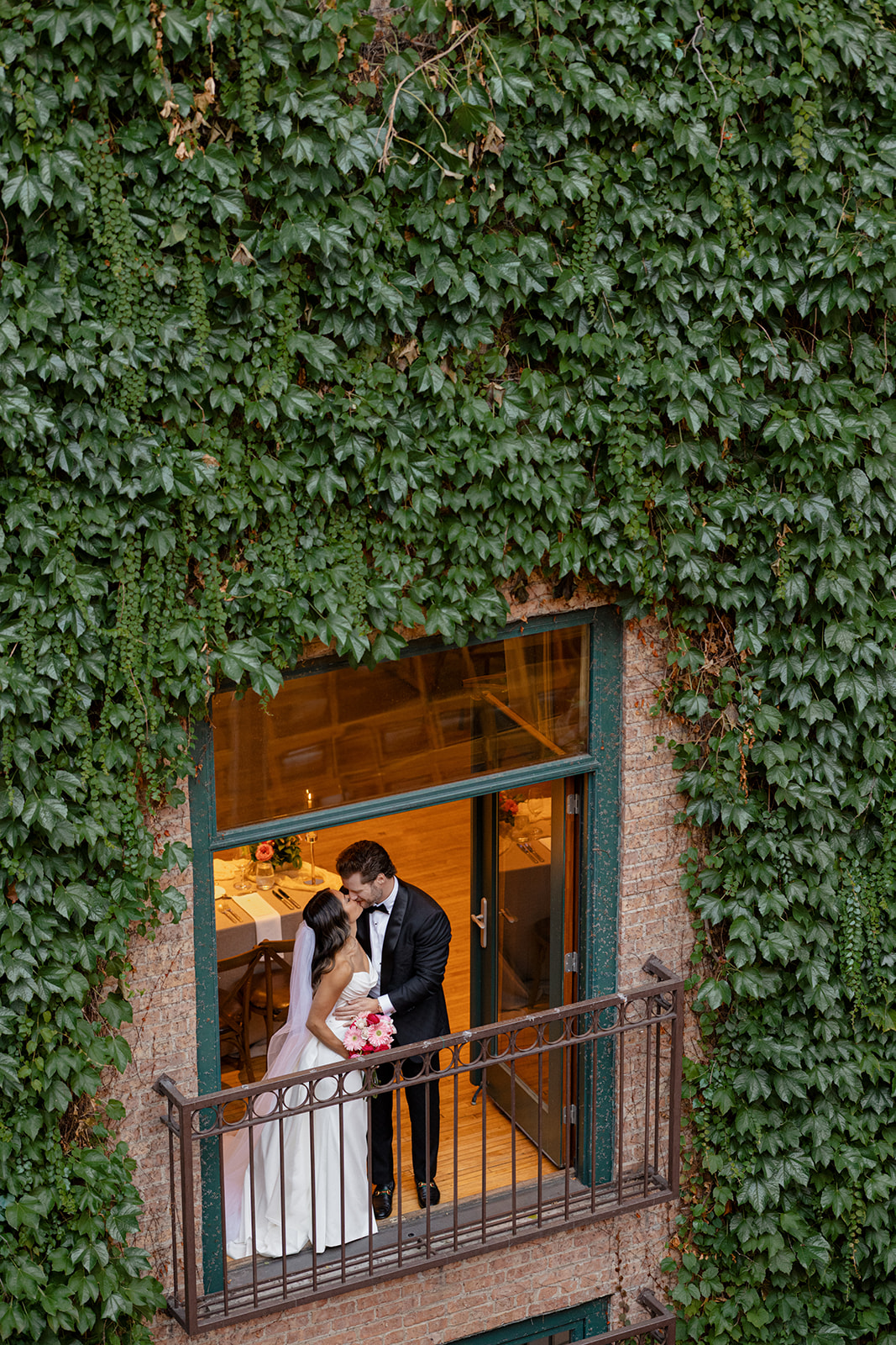 Bride and groom kissing on an ivy-covered balcony at The Ivy Room in Chicago wedding venue