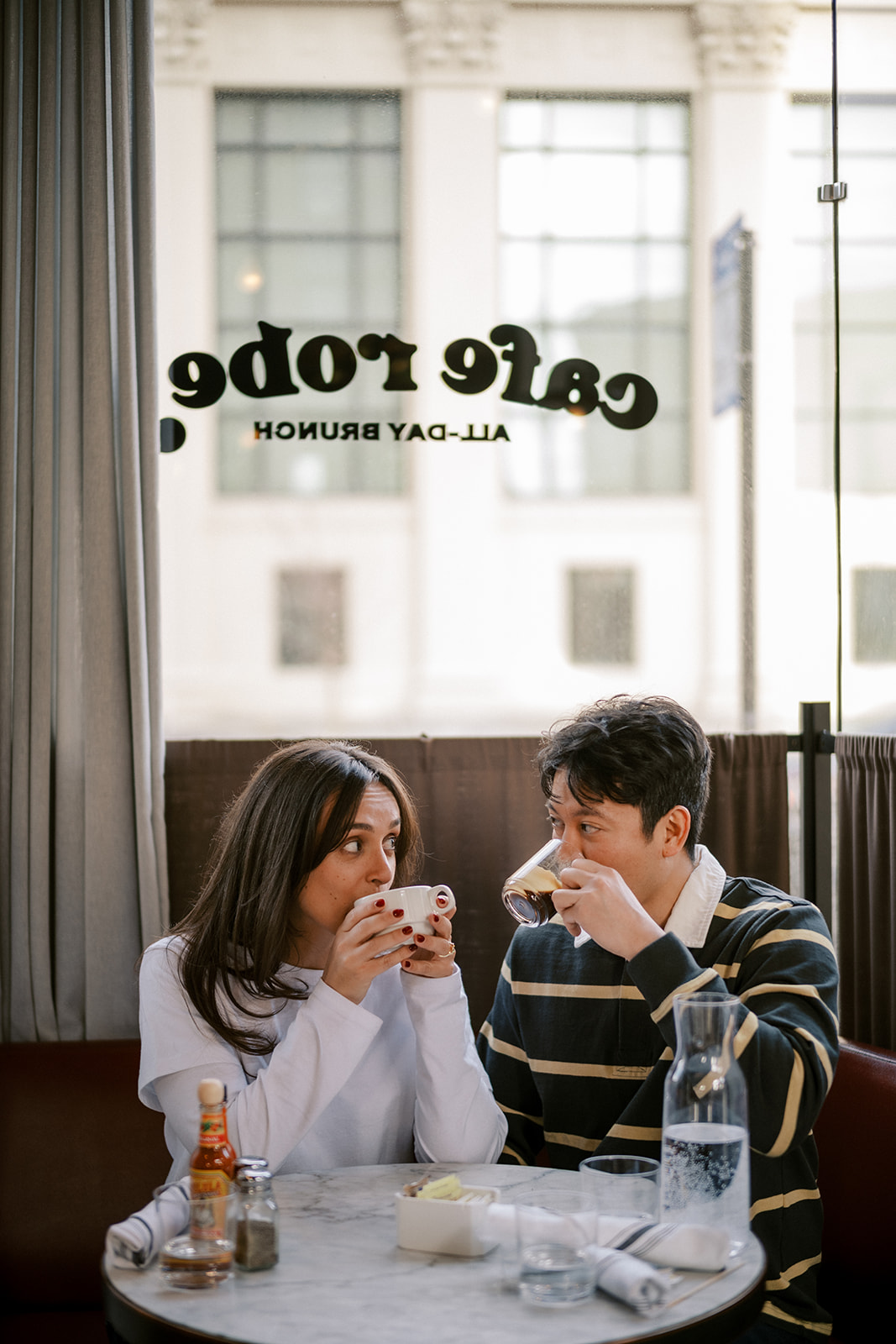 Couple sipping coffee at Cafe Robey during a Chicago engagement session, candid documentary photo