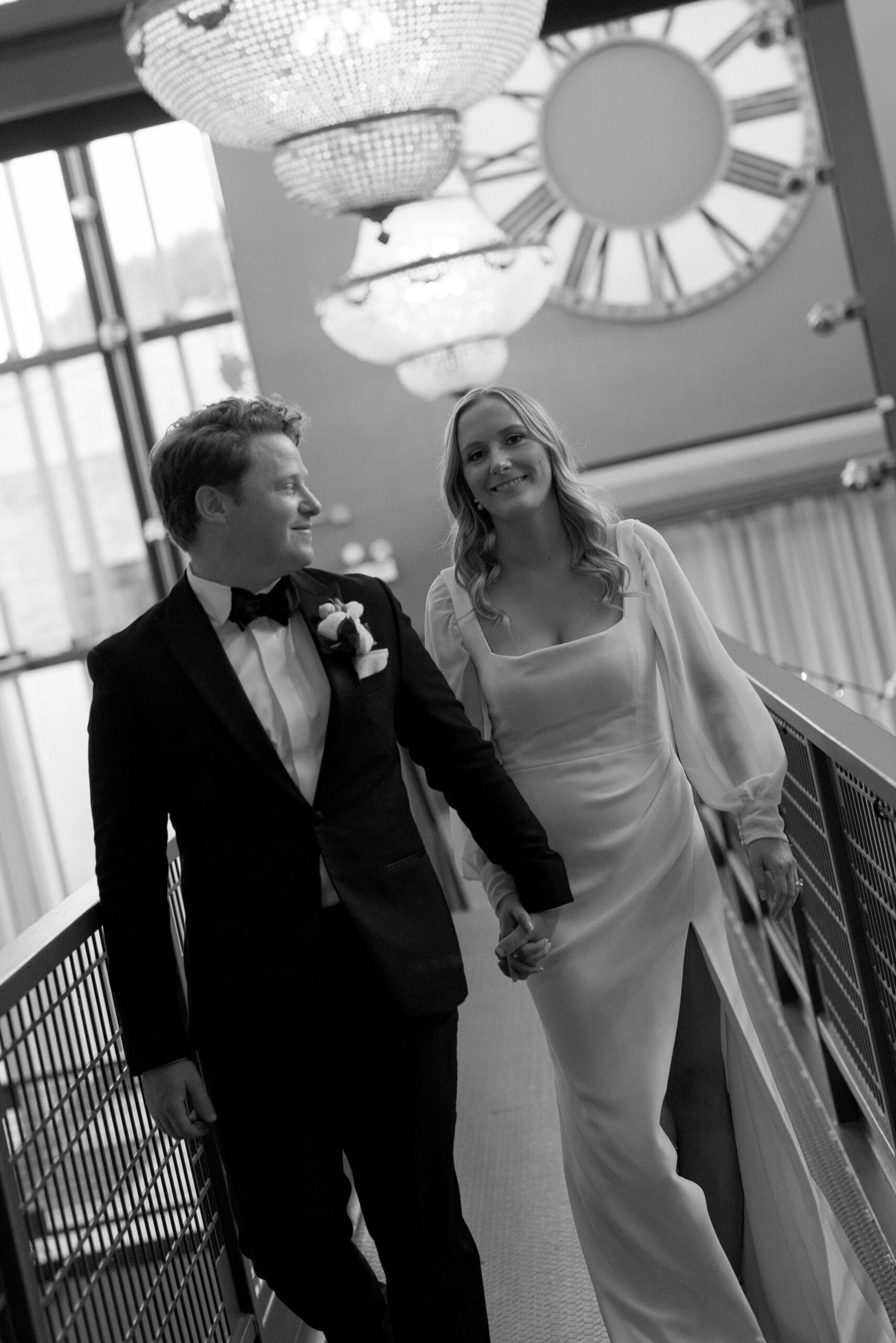 portrait of the bride and groom walking together at Artifact Events Chicago under chandelier lighting.