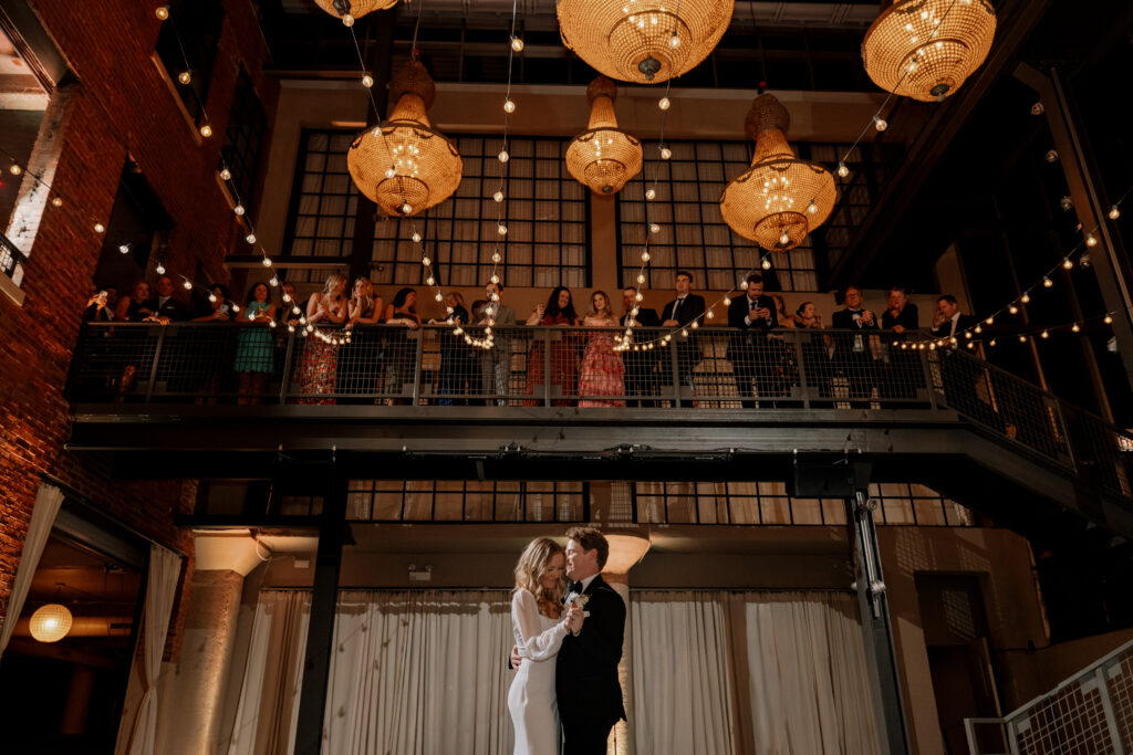 Bride and groom sharing a dance during their Artifact Events wedding reception in Chicago as guests watch from the mezzanine.